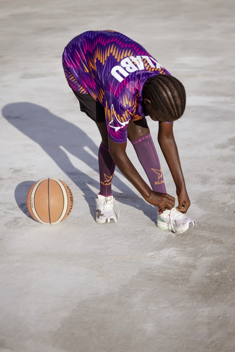 KLABU sporter bindt haar schoenen vast op een basketbalveld